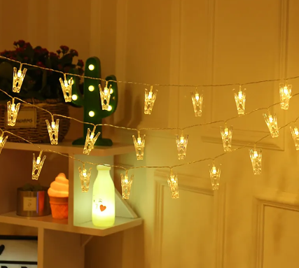 A warm, cozy indoor scene with clip lights strung across the room, each clip holding a transparent plastic piece, emitting a soft glow and creating a pleasant ambiance.
