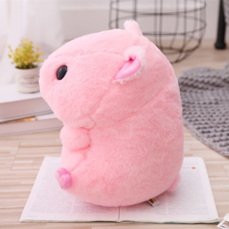 A side view of the piggy plushie on an open book, giving a sense of scale and showing the plushie's profile.