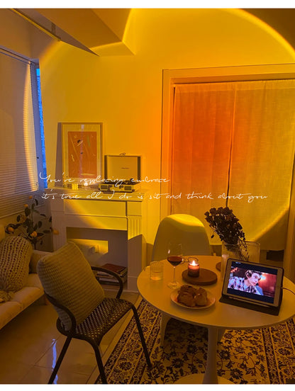 A romantic setup with a sunset projector casting a warm glow, a table set with wine, a candle, and a movie playing on a tablet, creating a dreamy room decor ambiance.