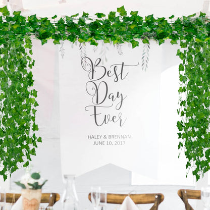 An elegant wedding backdrop with green ivy garlands over a sign reading "Best Day Ever," fitting a cottagecore room decor or event theme.