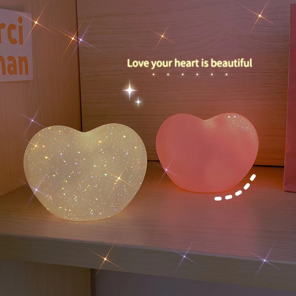 Two heart-shaped lamps placed on a shelf, one shining with star-like speckles and the other in a solid warm hue, creating a serene atmosphere that aligns with 'cottagecore-living-room' and 'dreamy-room-decor' collections.