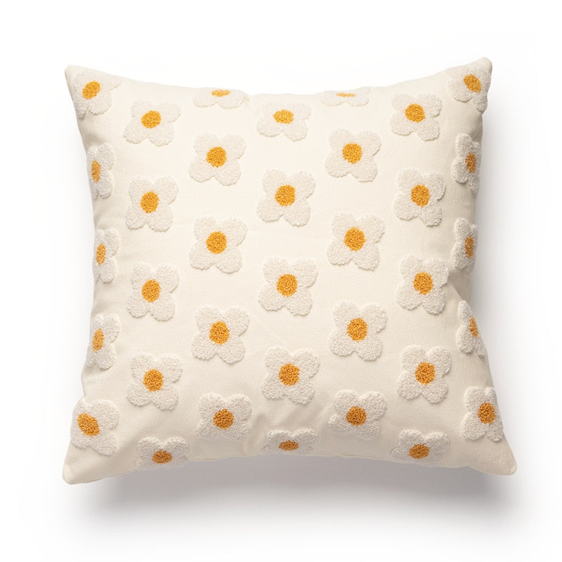 A square pillowcase featuring a cream background with a raised, tufted pattern of small daisy flowers, each with a golden yellow center and white petals. The design evokes a sense of warmth and is well-suited for various decor styles, including 'Art Hoe', 'Boho', 'Coquette', 'Cottagecore', 'Danish Pastel', suitable for a 'Dorm Room', 'Dreamy Room', 'Feminine Decor', or a 'Relaxing Room' setting.