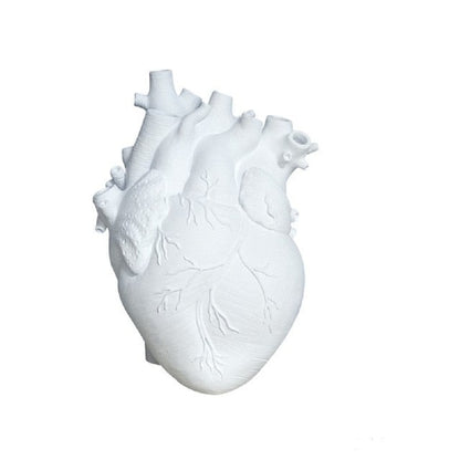A simple white heart-shaped vase captures the realistic details of a human heart, emphasizing the product's unique anatomical design.