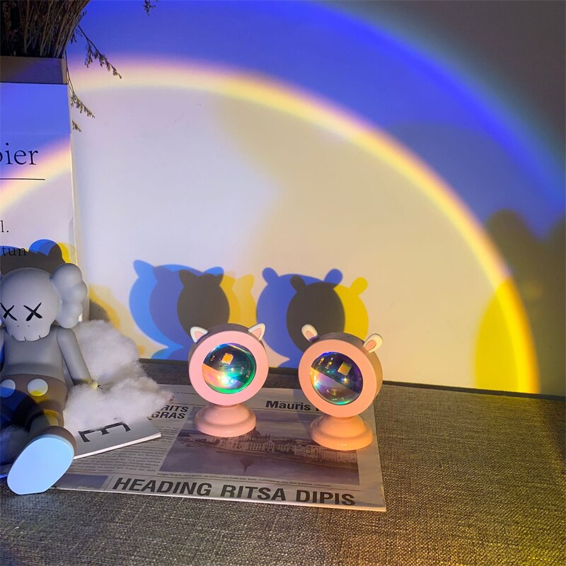 Twin cat-eared sunset light projectors casting a vibrant rainbow arc over a cozy setting, fitting perfectly into the lighting and dreamy-room decor collection alongside whimsical room accessories.