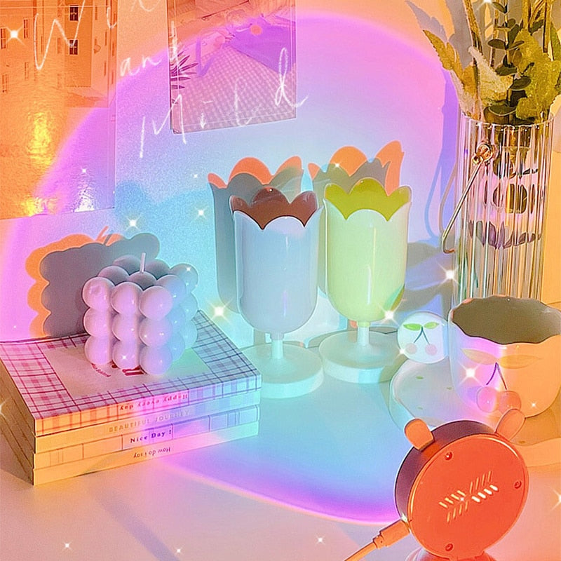 Colorful sunset light projector set amongst various room decor items including tulip-shaped glasses, contributing to a cheerful room decor and kawaii-room aesthetic with its pastel rainbow hues and soft lighting.