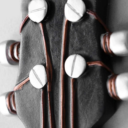 A macro photograph focused on the tuning pegs of a guitar headstock imitation, showing a black background with metallic pegs and brown winding details. The image captures the texture and contrast between the dark headstock and the shiny pegs, illustrating a close-up view of the craftsmanship.