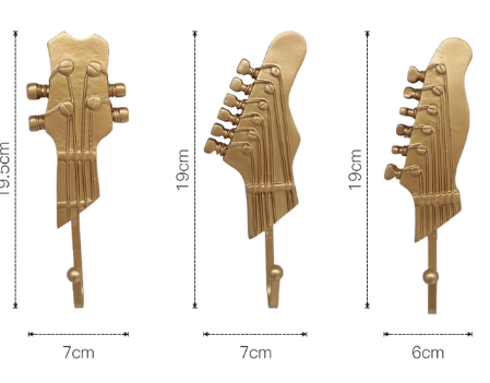 Three wooden guitar headstock-shaped wall hooks are shown side by side against a white background, each with dimensions indicated. The first two from the left are identical, measuring 7 cm in width and 19 cm in height, while the third is slightly narrower at 6 cm wide. Their wooden texture and detailed carving, including the tuning pegs and strings, give them a realistic and rustic appearance.