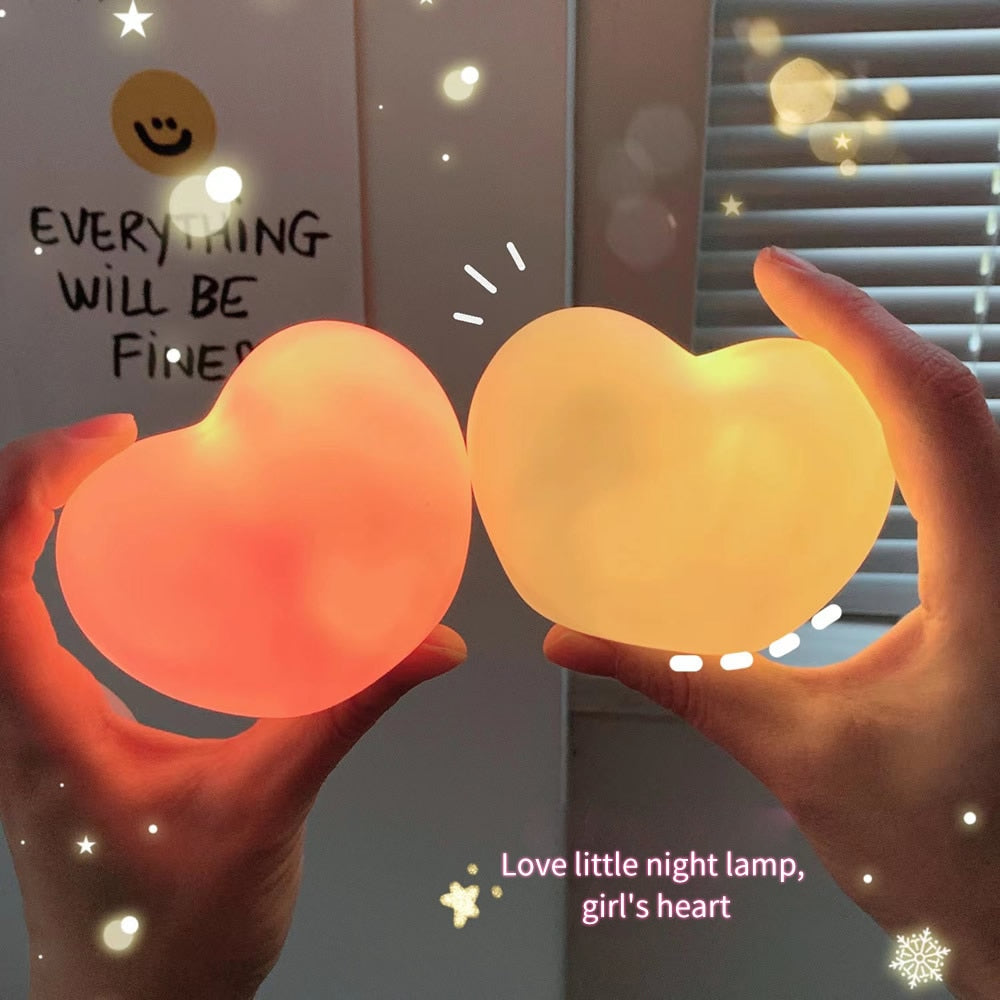 Hands holding two illuminated heart-shaped lamps, one emitting a warm red and the other a soft yellow light, casting a cozy ambiance suitable for 'cheerful-room-decor' and 'soft-girl-room' collections.