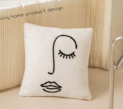 A close-up of a white, textured pillowcase with a black, continuous line drawing of a stylized eye with lashes, a nose, and full lips. This artistic pillowcase is part of the 'Art Hoe' collection and fits a variety of interior design themes such as 'Boho', 'Coquette', 'Cottagecore', 'Danish Pastel', and more. 